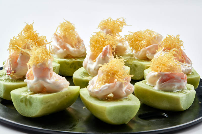 黑色瓷盘装的沙拉大虾仁图片