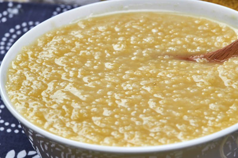 手持木勺㧟起的美味香浓小米粥图片