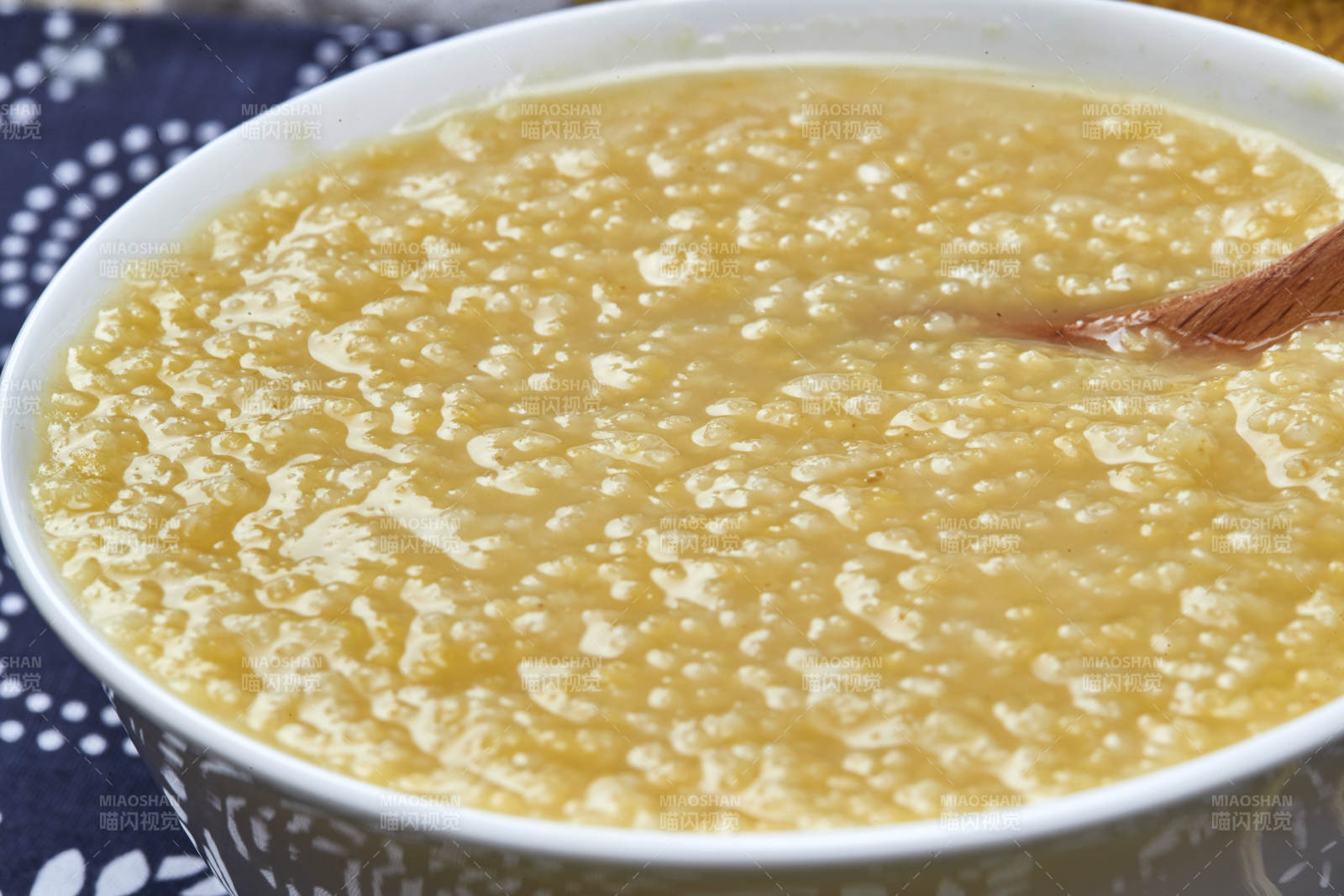 手持木勺㧟起的美味香浓小米粥图片