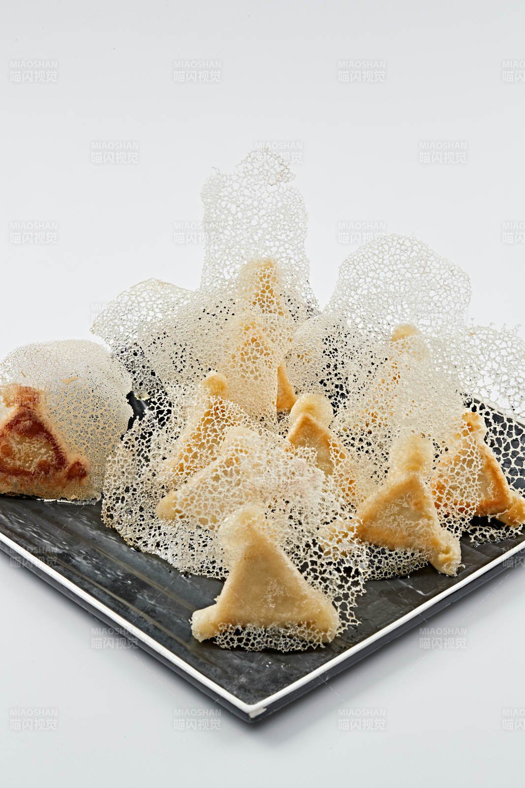 黑色瓷盘装的渔网水煎包图片