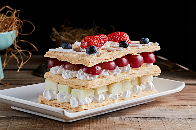 白色瓷盘装的水果戚风奶油拿破仑蛋糕图片
