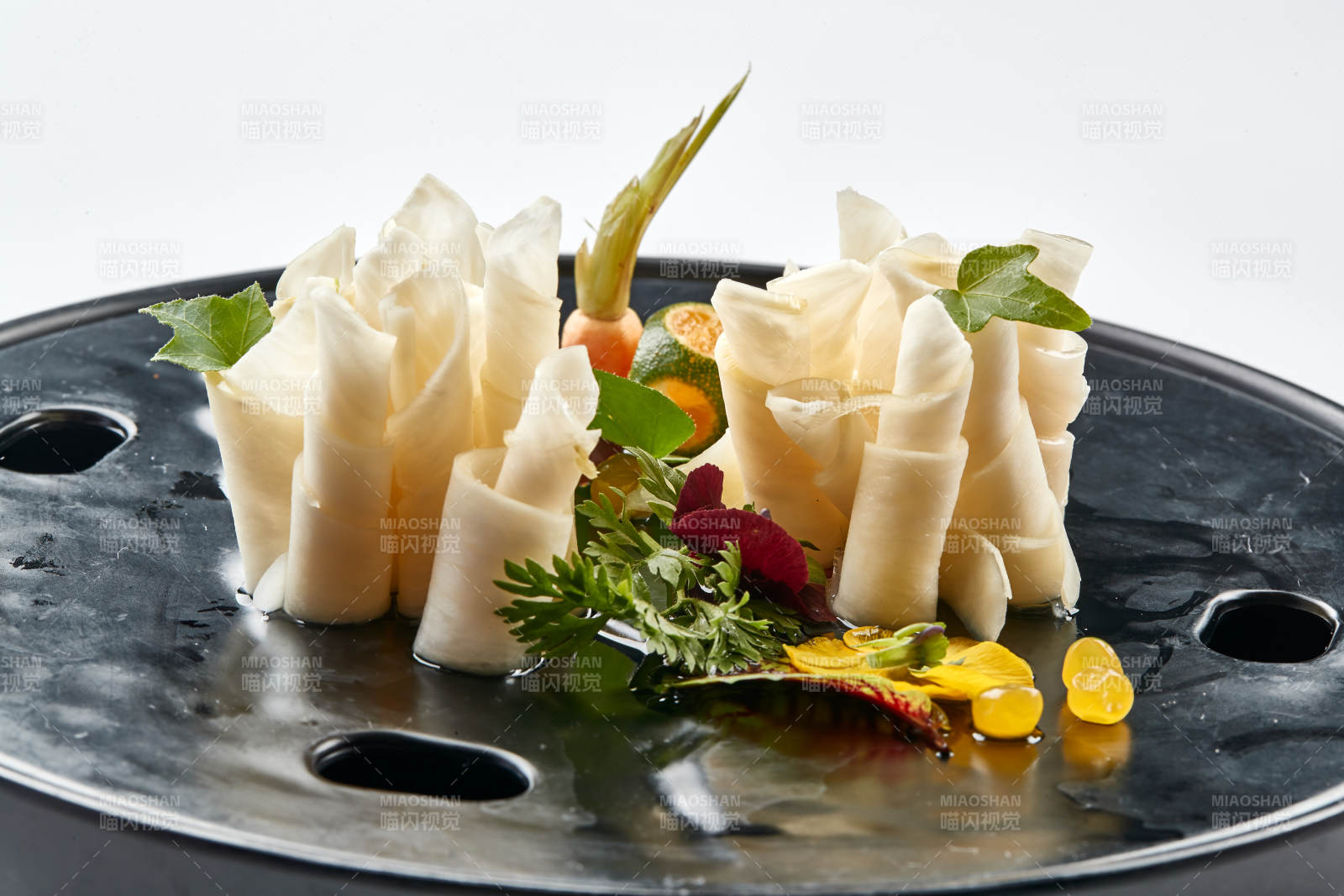 黑色瓷餐具装的鲜杏鲍菇刺身卷图片