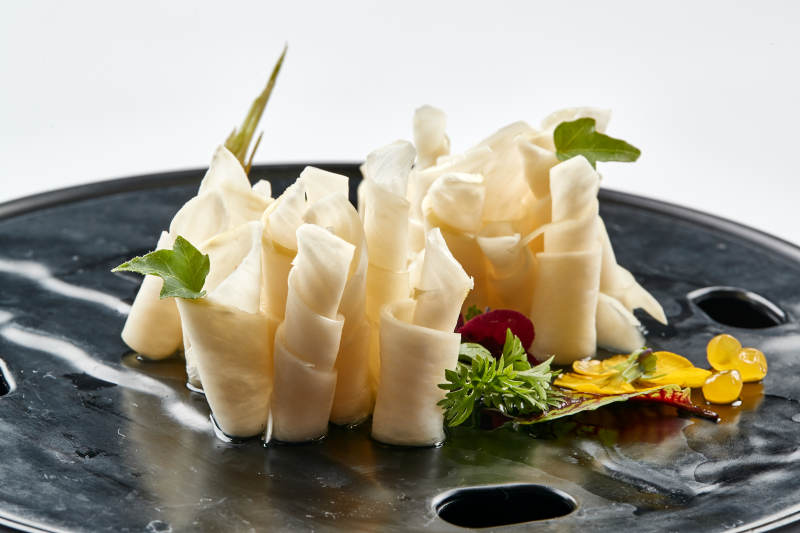 黑色瓷餐具装的鲜杏鲍菇刺身卷图片