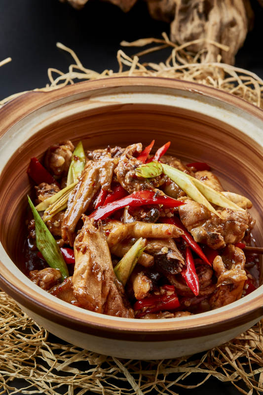 黑色背景上的砂锅酱香鸡块煲图片