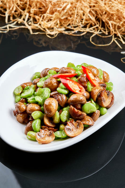 白色瓷盘装的塞外口蘑小炒青蚕豆图片