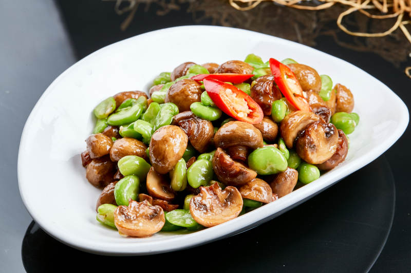 白色瓷盘装的塞外口蘑小炒青蚕豆图片