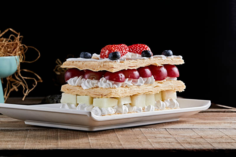 白色瓷盘装的水果戚风奶油拿破仑蛋糕图片