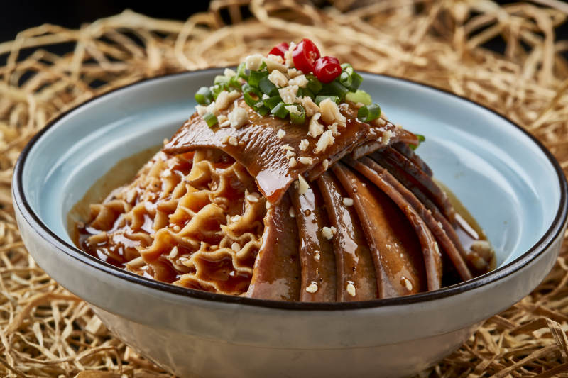 黑色背景上的瓷餐具装的川味夫妻肺片图片