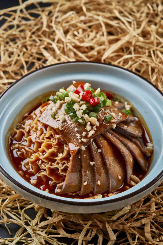 黑色背景上的瓷餐具装的川味夫妻肺片图片