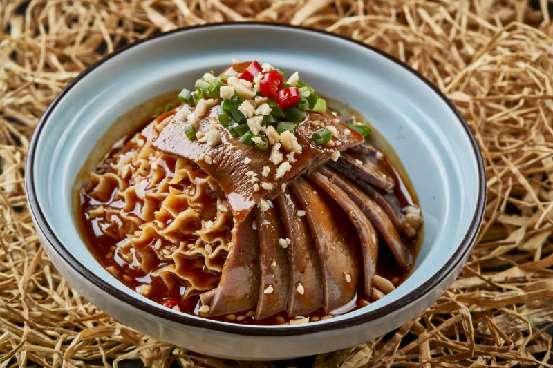 黑色背景上的瓷餐具装的川味夫妻肺片图片