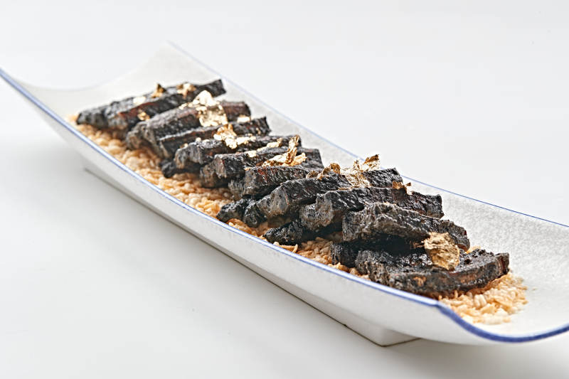 白色瓷盘装的墨鱼汁香煎猪五花肉图片