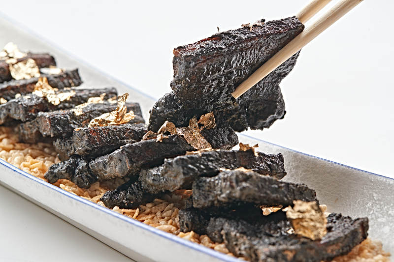 白色瓷盘装的墨鱼汁香煎猪五花肉图片