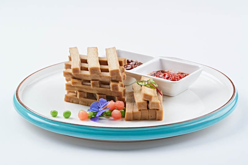 白色瓷盘装的蘸酱烟熏豆干图片