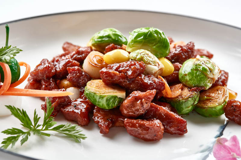 白色瓷盘装的酱爆银杏小甘蓝黑胡椒牛仔粒图片