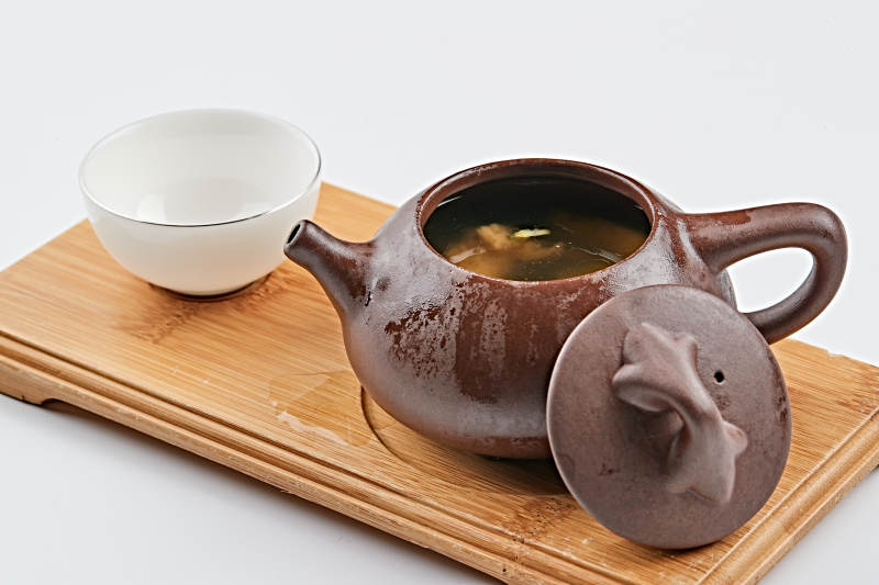 白色背景上摆放的紫砂当归土鸡汤图片