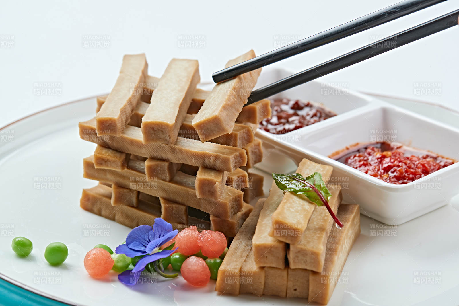 白色瓷盘装的蘸酱烟熏豆干图片