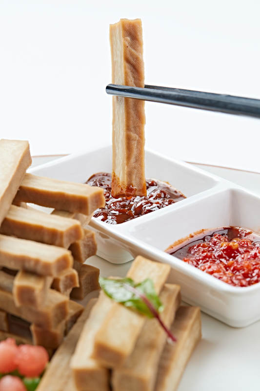 白色瓷盘装的蘸酱烟熏豆干图片