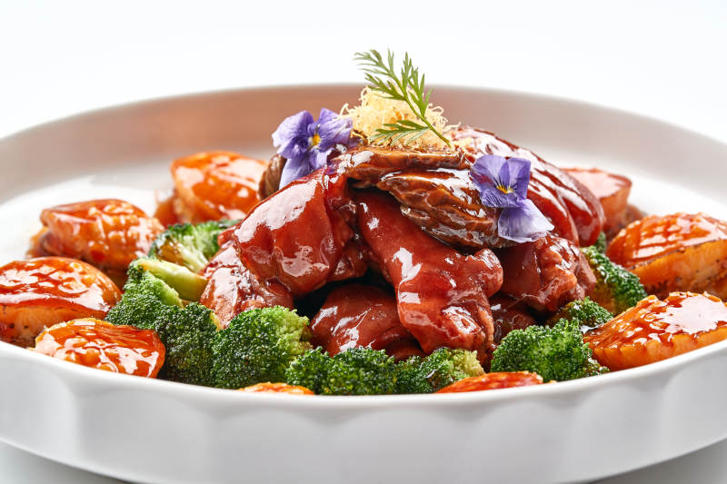 白色瓷盘装的酱烧猪肘鲜鲍鱼图片