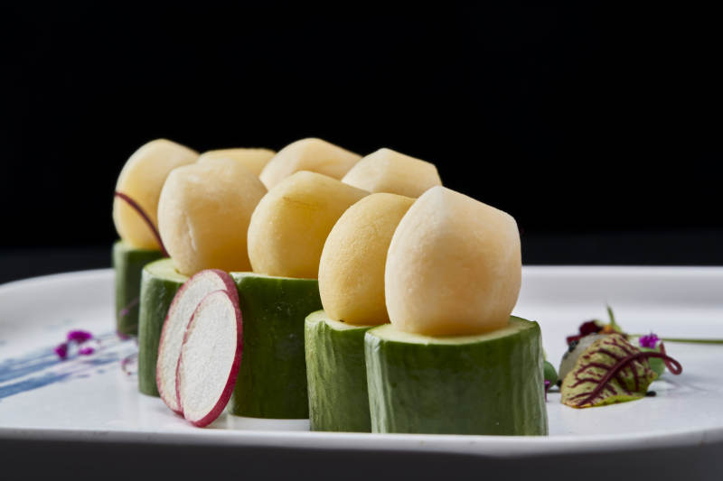 黑色背景上的创意美食手打马铃薯球配乳瓜段图片