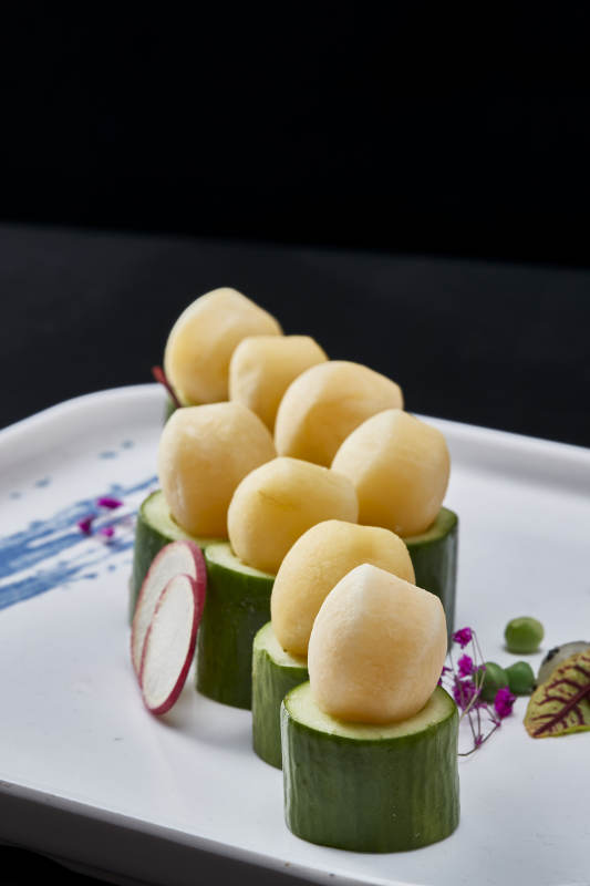 黑色背景上的创意美食手打马铃薯球配乳瓜段图片