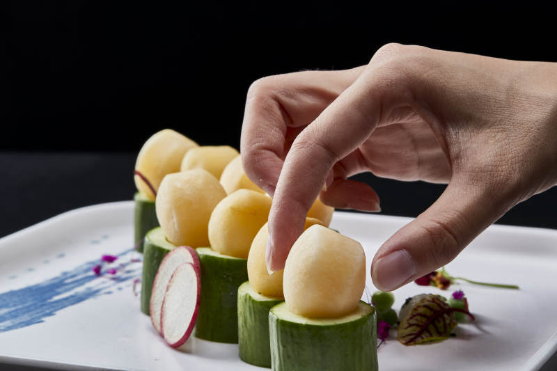 黑色背景上的创意美食手打马铃薯球配乳瓜段图片