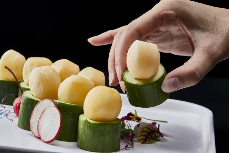 黑色背景上的创意美食手打马铃薯球配乳瓜段图片