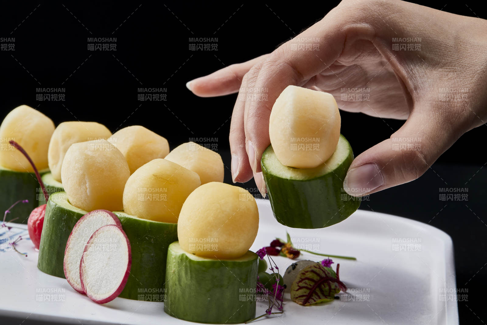 黑色背景上的创意美食手打马铃薯球配乳瓜段图片