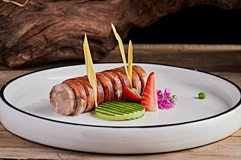 白色瓷盘装的精美凉菜肘花切片图片