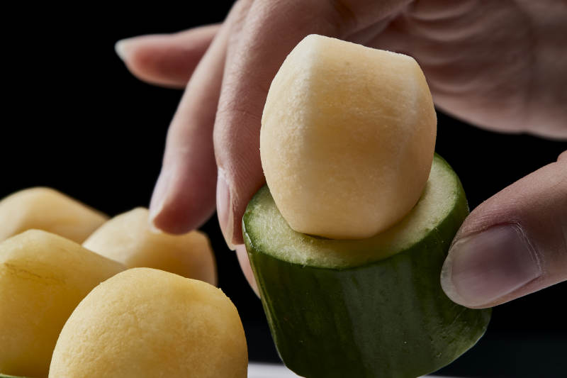 黑色背景上的创意美食手打马铃薯球配乳瓜段图片