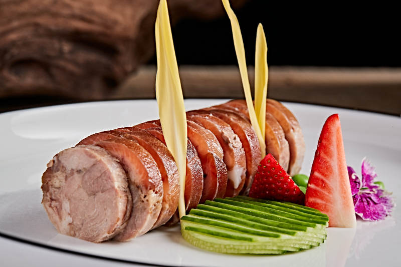 白色瓷盘装的精美凉菜肘花切片图片