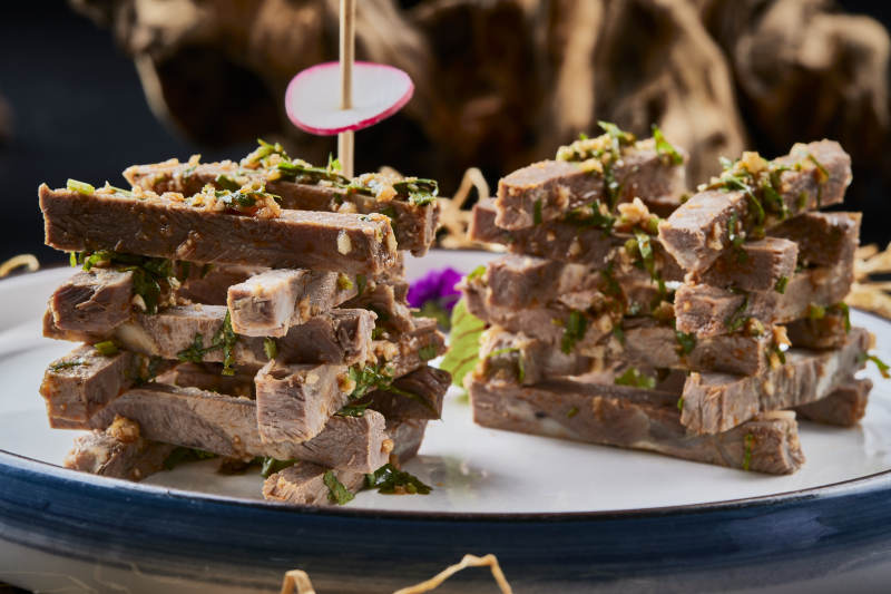 白色圆瓷盘装的蒜香小驴肉图片