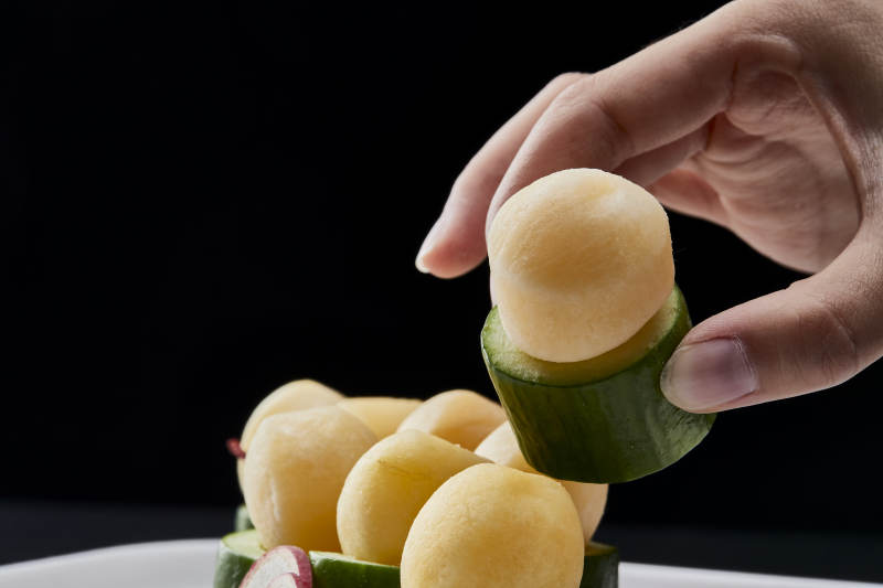 黑色背景上的创意美食手打马铃薯球配乳瓜段图片