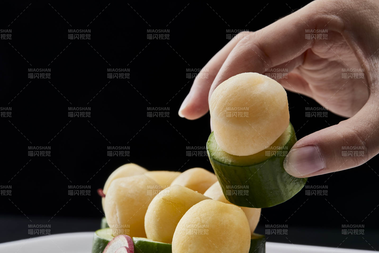 黑色背景上的创意美食手打马铃薯球配乳瓜段图片
