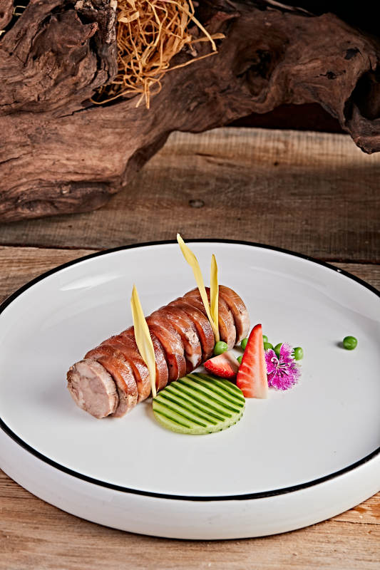 白色瓷盘装的精美凉菜肘花切片图片