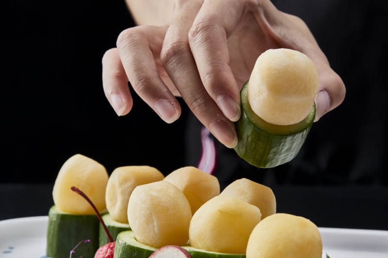 黑色背景上的创意美食手打马铃薯球配乳瓜段图片