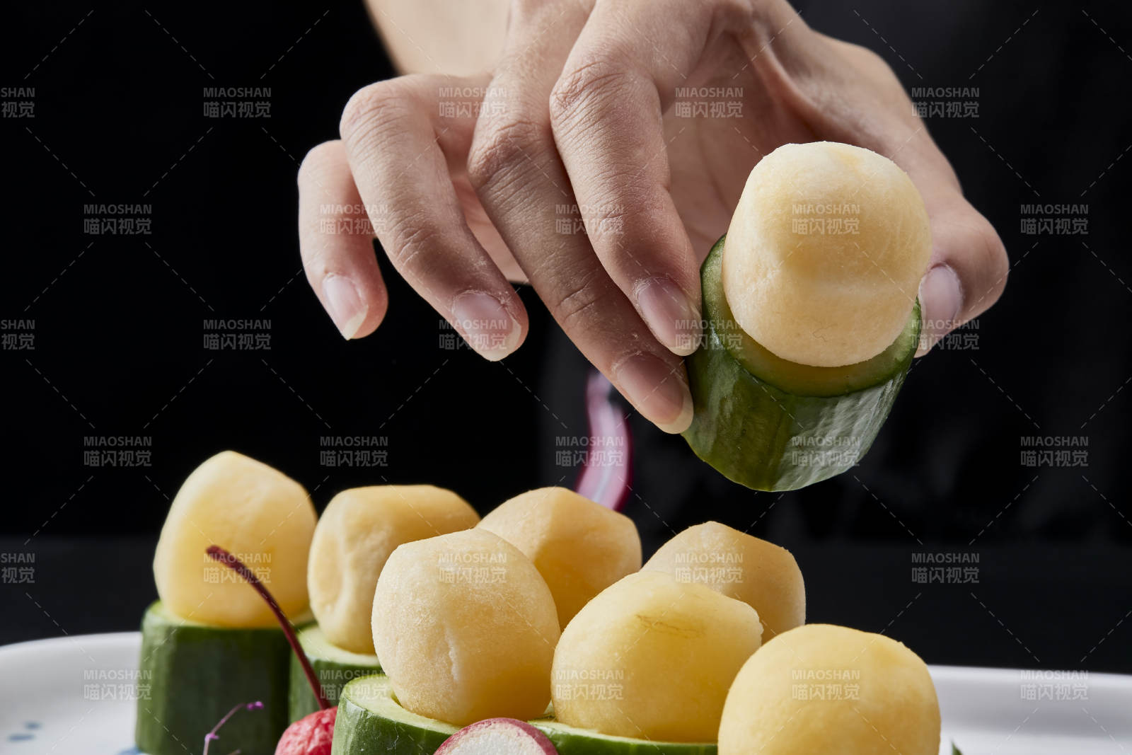 黑色背景上的创意美食手打马铃薯球配乳瓜段图片