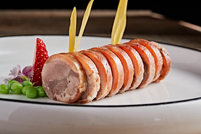 白色瓷盘装的精美凉菜肘花切片图片