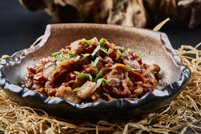 黑色背景上的陶碗装的肥肉炒瘦肉图片