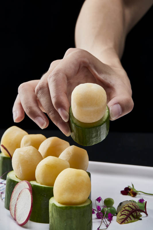 黑色背景上的创意美食手打马铃薯球配乳瓜段图片