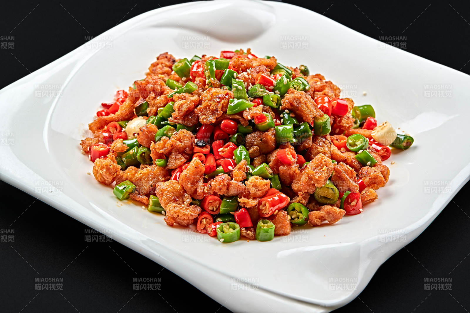 白色瓷盘装的川香口味鲜椒爆鸡丁图片