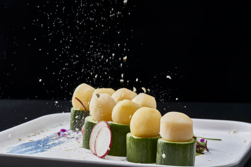 黑色背景上的创意美食手打马铃薯球配乳瓜段图片