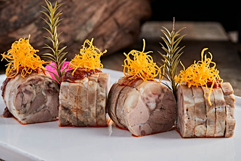 白色瓷盘装的精美凉菜肘花切片图片