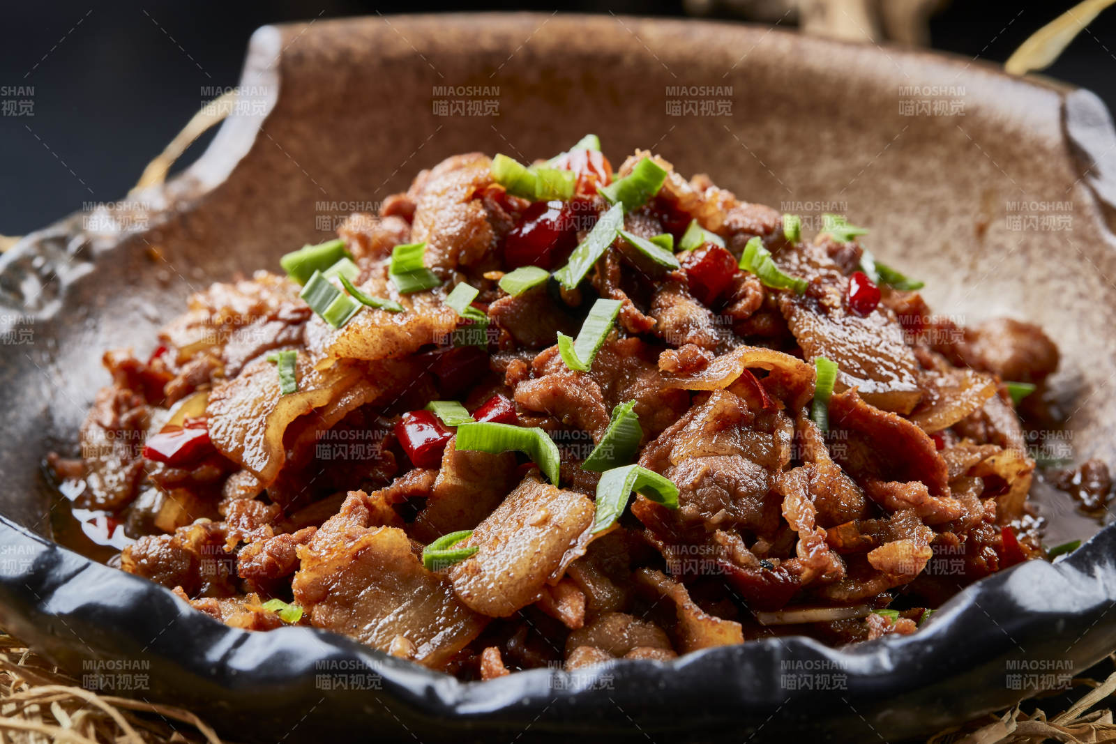 黑色背景上的陶碗装的肥肉炒瘦肉图片