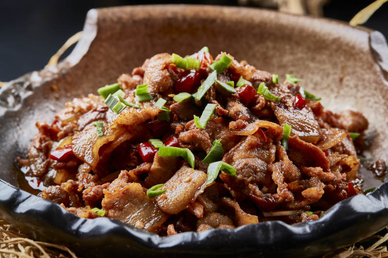 黑色背景上的陶碗装的肥肉炒瘦肉图片