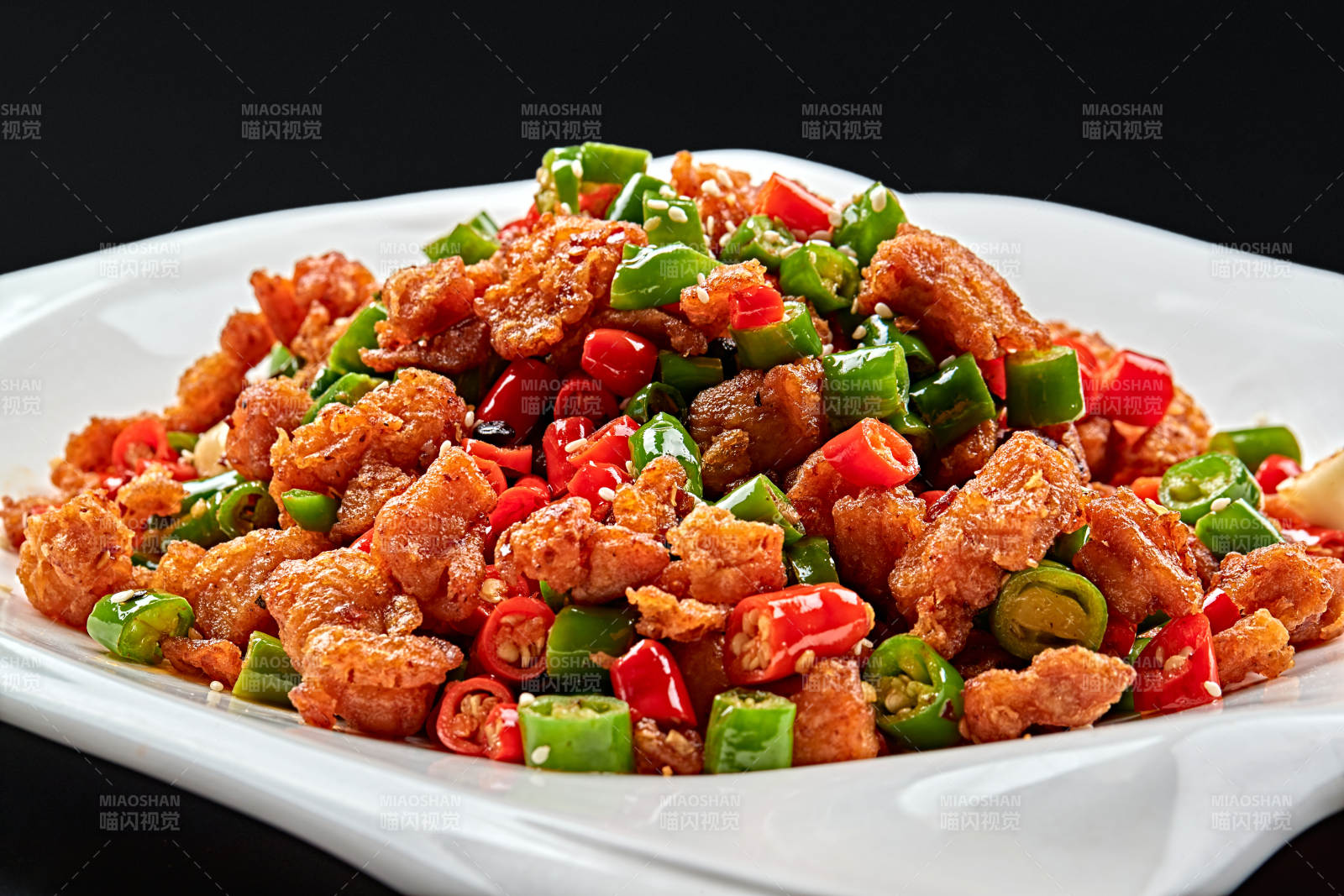 白色瓷盘装的川香口味鲜椒爆鸡丁图片