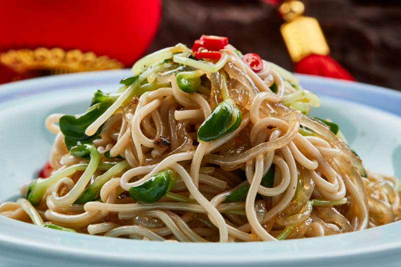 青色瓷餐具装的黑豆苗凉拌莜面饸饹图片