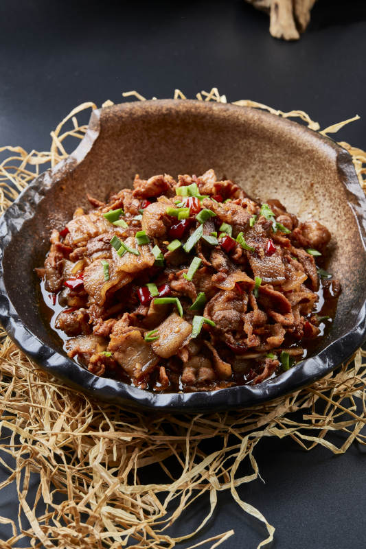 黑色背景上的陶碗装的肥肉炒瘦肉图片