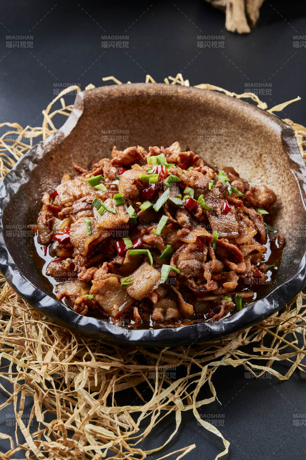 黑色背景上的陶碗装的肥肉炒瘦肉图片