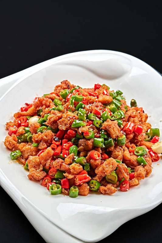 白色瓷盘装的川香口味鲜椒爆鸡丁图片