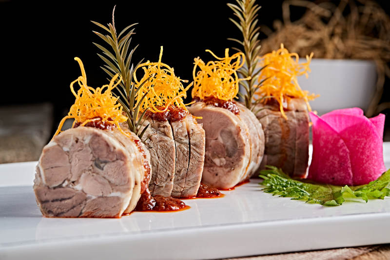 白色瓷盘装的精美凉菜肘花切片图片